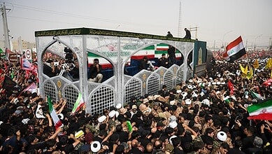 Large crowd of mourners gathered in Qom with flags and banners for Khamenei's farewell ceremony.