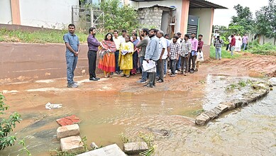Group of residents and officials examining sewage entering pond in Hyderabad.