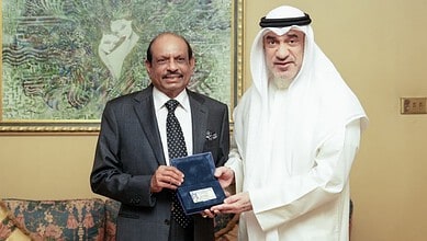 Yusuff Ali receiving Kuwait's Golden Residency from an official in traditional attire.