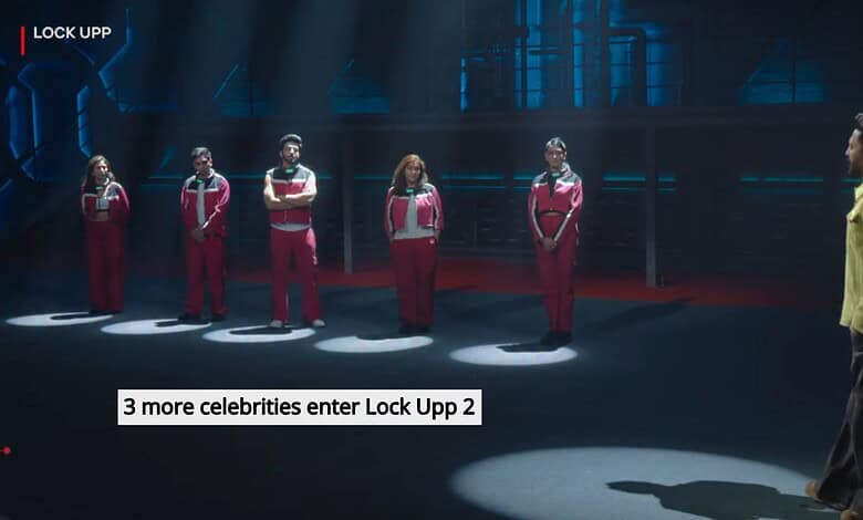 Five contestants in red and white uniforms face a man in a yellow shirt on a dark stage.