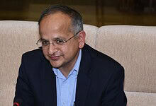 Indian official in formal attire during a press conference or meeting.