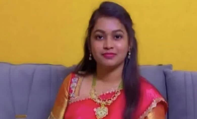 Young woman in traditional attire sitting on a sofa against a yellow wall.