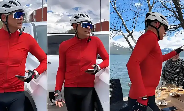Female cyclist in red jacket and helmet using smartphone outdoors.