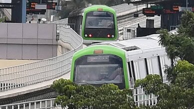Green and white metro train moving on elevated track in Hyderabad.