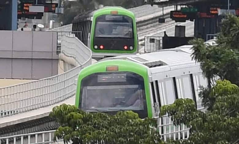 Green and white metro train moving on elevated track in Hyderabad.