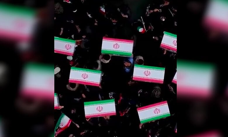 Flag-draped coffins are carried by mourners during a funeral procession in Minab for 34 victims identified through DNA testing following the Shajareh Tayyebeh Elementary School strike.