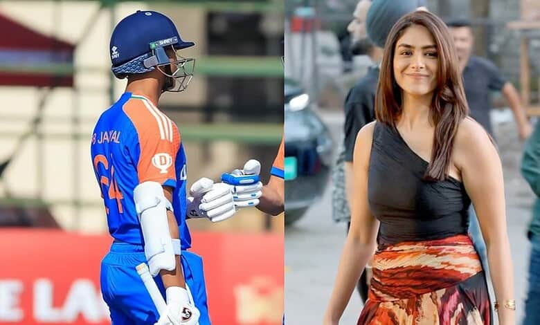Indian cricketer in blue uniform with helmet and gloves at a cricket ground.