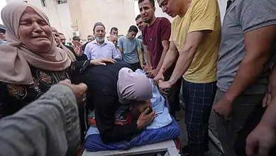 A woman mourns as others gather around in a scene of grief in the West Bank.
