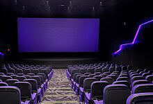 Empty modern cinema theatre with purple lighting and large screen in Hyderabad.