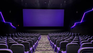 Empty modern cinema theatre with purple lighting and large screen in Hyderabad.