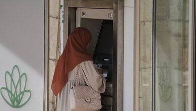 Woman in hijab using an ATM machine in the West Bank, Palestine.