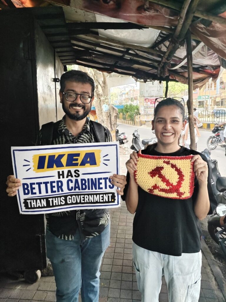 Protesters holding signs and a bag with communist symbols in an urban setting.
