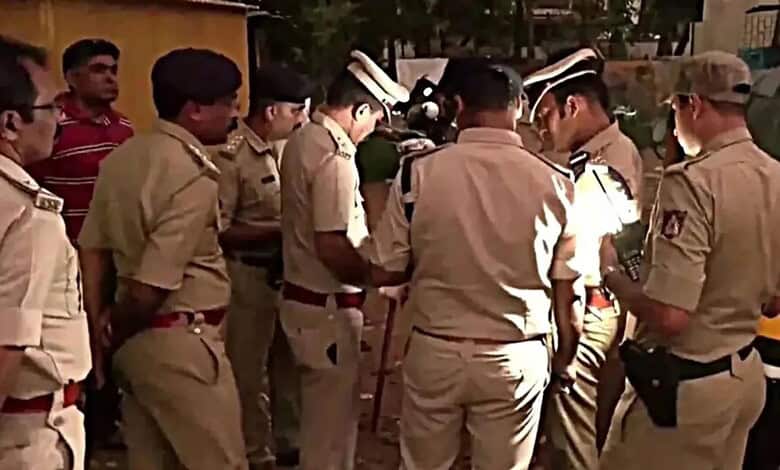 Police officers gather around a suspect during an investigation in Bellandur.