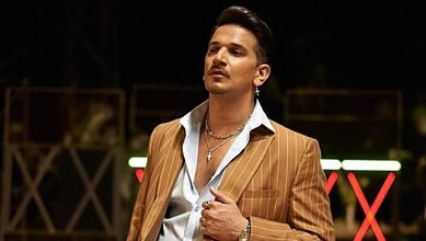 Prince Narula in a brown pinstripe suit during a public event or interview.