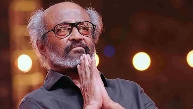 Rajinikanth in a thoughtful pose with hands folded, wearing glasses and a black shirt.