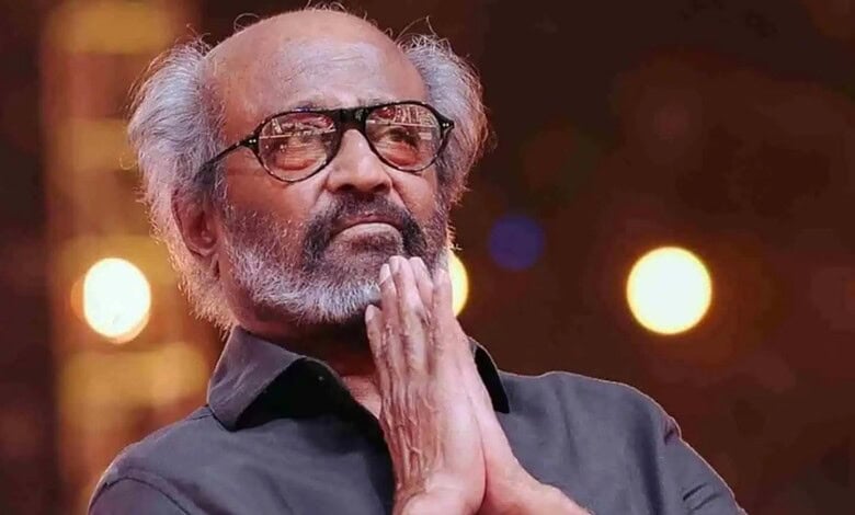 Rajinikanth in a thoughtful pose with hands folded, wearing glasses and a black shirt.