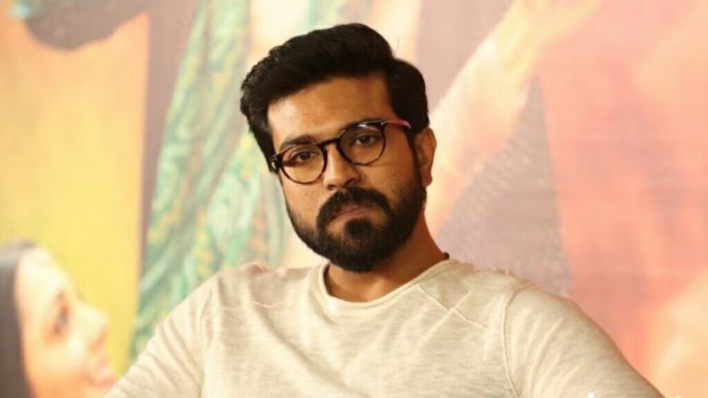 Ram Charan with glasses and beard in a casual setting, looking serious.