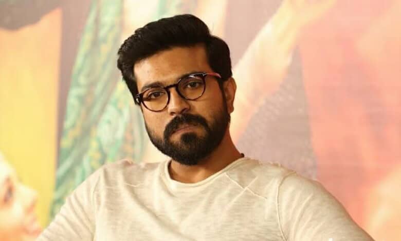Ram Charan with glasses and beard in a casual setting, looking serious.