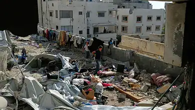 People search through debris and damaged belongings in a destroyed building in Gaza City.