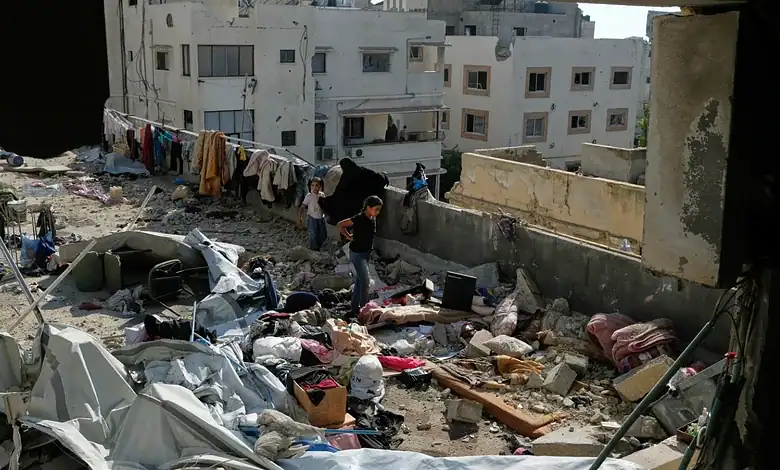 People search through debris and damaged belongings in a destroyed building in Gaza City.