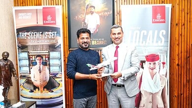 Revanth and Emirates representative exchanging documents at promotional event.
