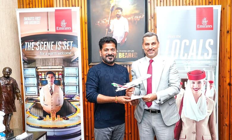 Revanth and Emirates representative exchanging documents at promotional event.