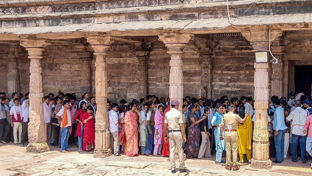 Crowd of people waiting in line for Friday prayers at Bhojshala under a stone structure.