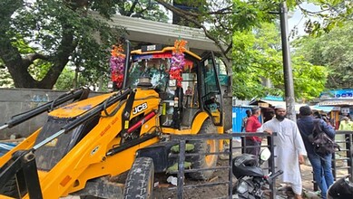 Construction vehicle and people during anti-encroachment operation in Bengaluru.