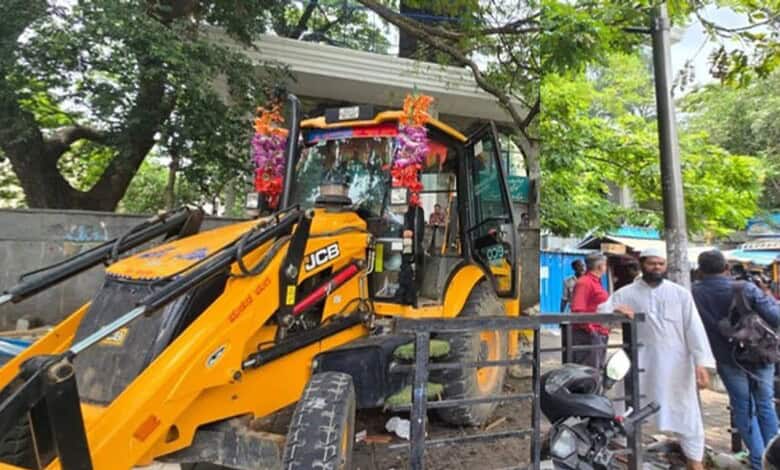Construction vehicle and people during anti-encroachment operation in Bengaluru.