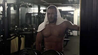Salman Khan shirtless in gym with a towel on his head, working out intensely.