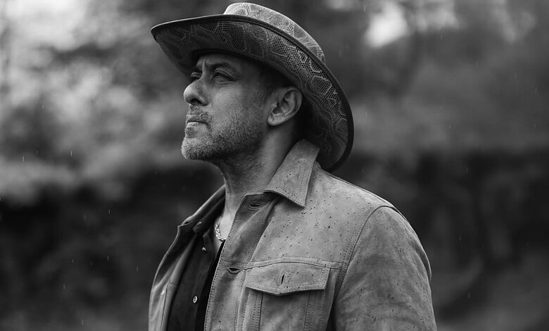 Salman Khan in a black and white photo wearing a hat and casual shirt.
