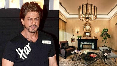 Shah Rukh Khan in a black T-shirt with 'Har' written on it, standing indoors.