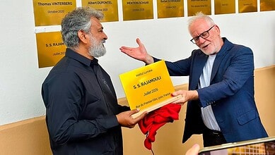 S. S. Rajamouli receiving a plaque from a man in a blue suit at the Lumiere Institute.