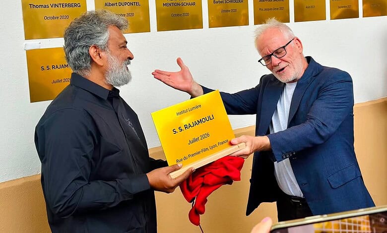 S. S. Rajamouli receiving a plaque from a man in a blue suit at the Lumiere Institute.