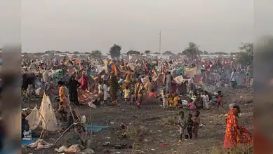 Refugees and tents in a crowded Sudan conflict camp with children and families.