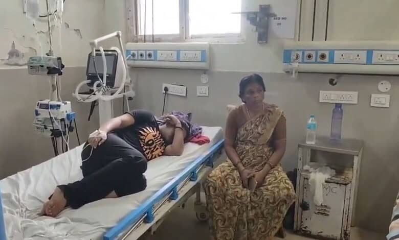 Patient lying on hospital bed with a woman sitting nearby in a hospital room.