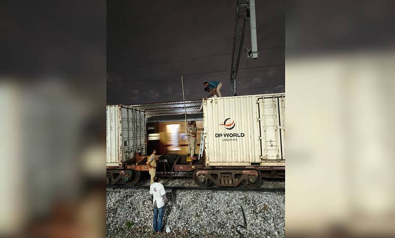 Person climbing on top of a goods train at night, with another person watching below.