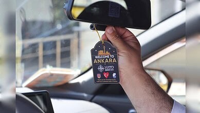 Person holding a car rearview mirror with Ankara welcome tag hanging from it.