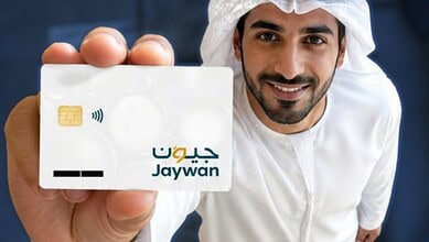Man holding UAE Jaywan card with contactless payment symbol, smiling at camera.