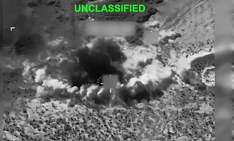 Unclassified military drone strike with explosion and smoke in desert terrain.