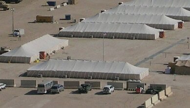 Aerial view of military tents and vehicles at a base in Kuwait, possibly related to US military presence.