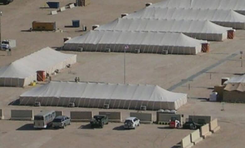 Aerial view of military tents and vehicles at a base in Kuwait, possibly related to US military presence.