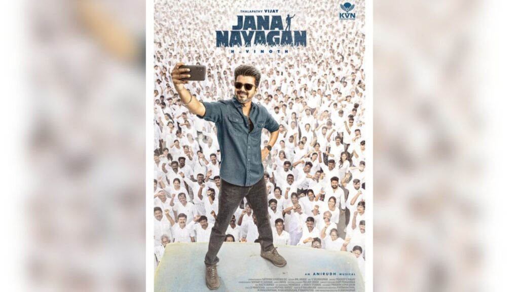 Vijay taking a selfie on stage with a large crowd in the background.