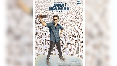 Vijay taking a selfie on stage with a large crowd in the background.