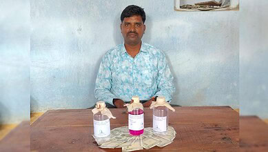 Man sitting at a table with bottles of sanitizer and cash, indoor setting.