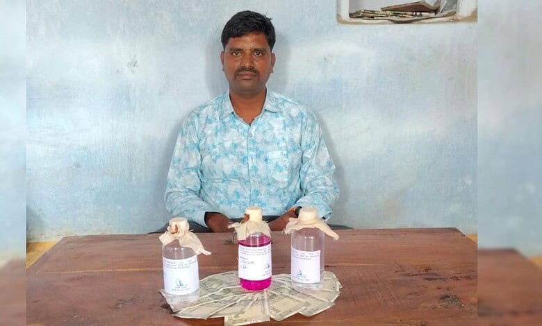 Man sitting at a table with bottles of sanitizer and cash, indoor setting.
