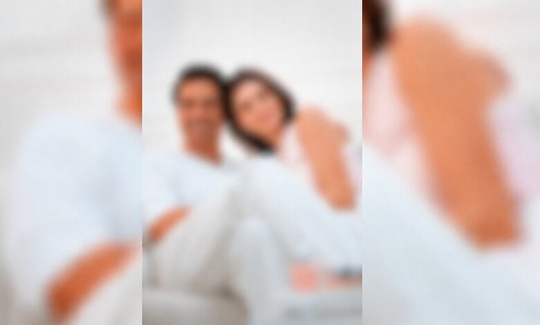 Blurred image of a couple celebrating a wedding, with a man and woman smiling.