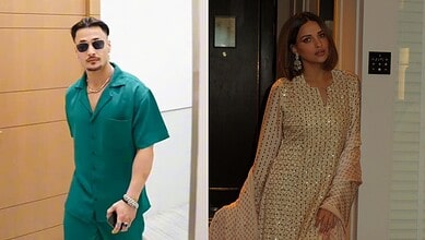 Stylish man in teal outfit and sunglasses, woman in beige traditional dress with embroidery.