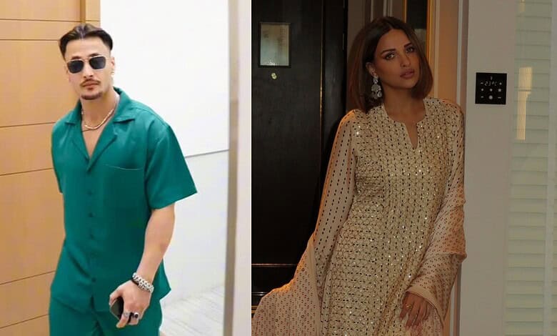 Stylish man in teal outfit and sunglasses, woman in beige traditional dress with embroidery.