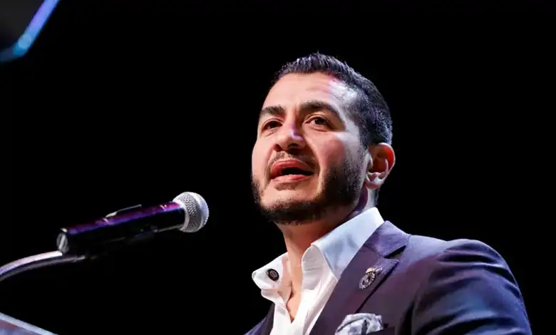 Abdul El-Sayed delivering speech at a public event in a suit and white shirt.